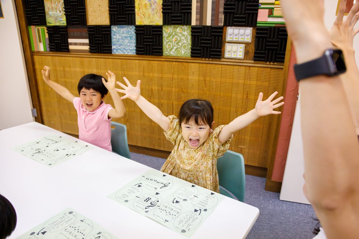 両手を挙げて音楽を楽しむ子どもたち